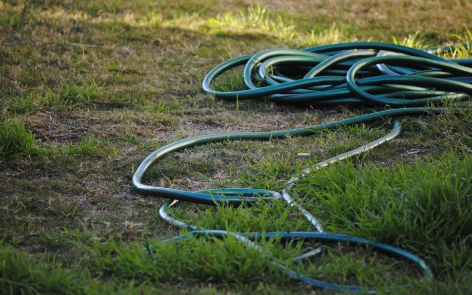 A tangled garden hose strewn on a patchy lawn.