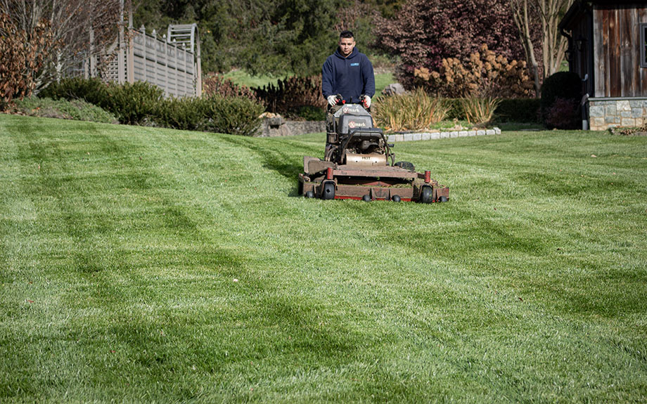 Riverbend crew member using a stand-on mower to mow a large lawn in northern Virginia.